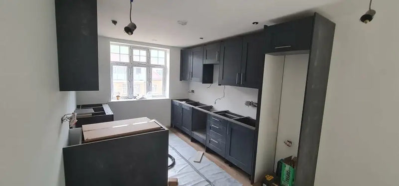 Navy blue shaker kitchen units being installed in a London property with wall and base cabinets fitted by ODS Plumbing & Construction