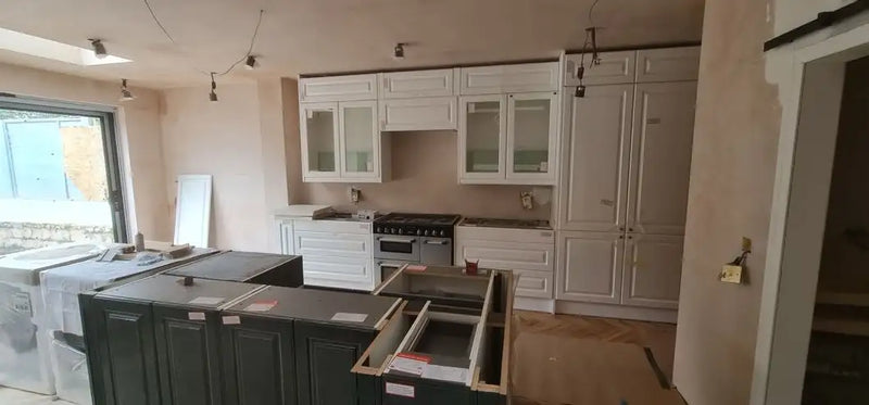 Traditional shaker kitchen mid-installation with dark island unit and range cooker in a London house extension by ODS Plumbing & Construction
