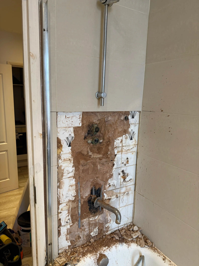 Old shower enclosure being stripped out with exposed pipework and tile removal in a London bathroom by ODS Plumbing & Construction