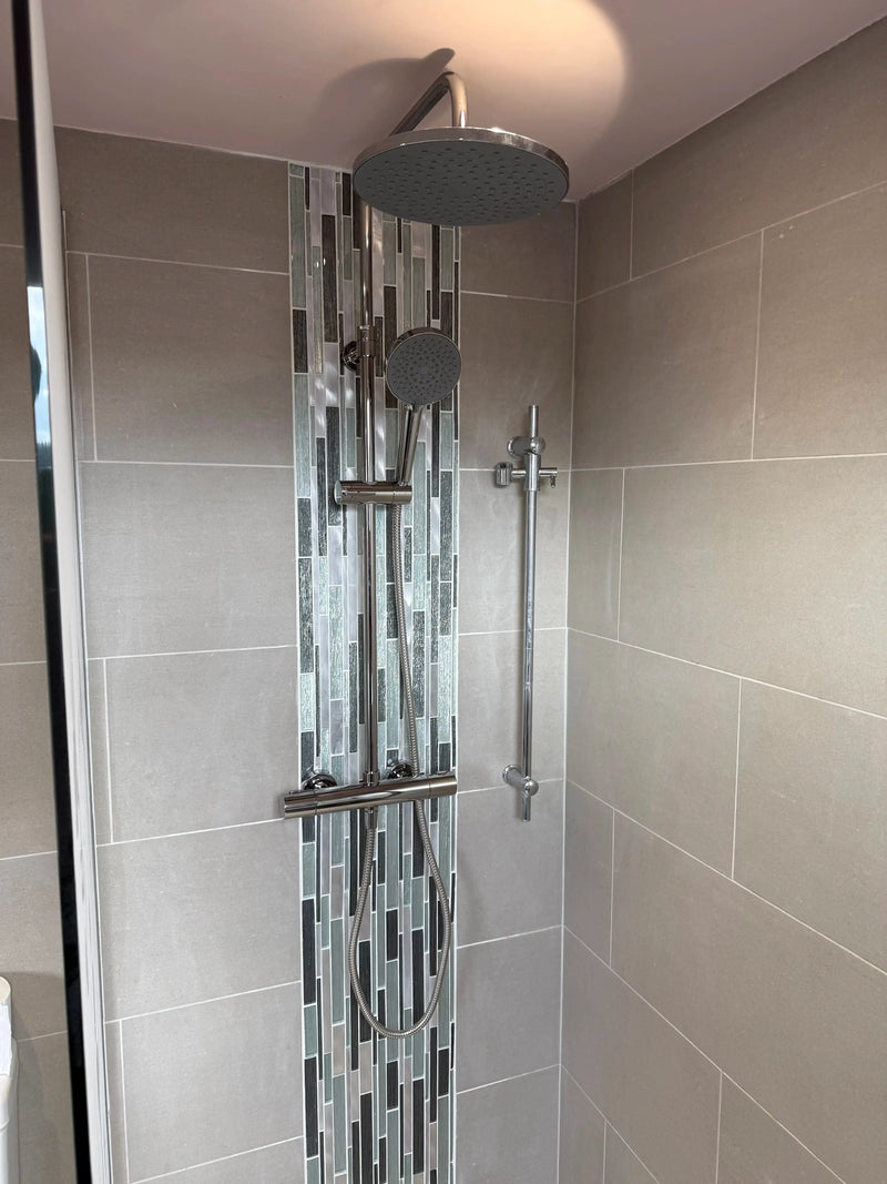 Chrome thermostatic rainfall shower with hand shower and vertical mosaic feature tile strip in a grey London bathroom by ODS Plumbing & Construction