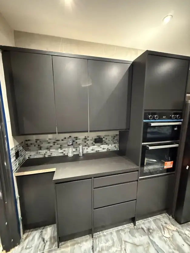 Matte graphite handleless kitchen with integrated double oven, dark worktop and mosaic tile splashback in London by ODS Plumbing & Construction