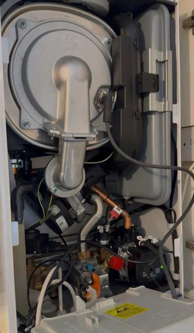 Technical view of the internal workings of a gas boiler, including the heat exchanger, fan, and pump, during a service by ODS Plumbing & Construction.