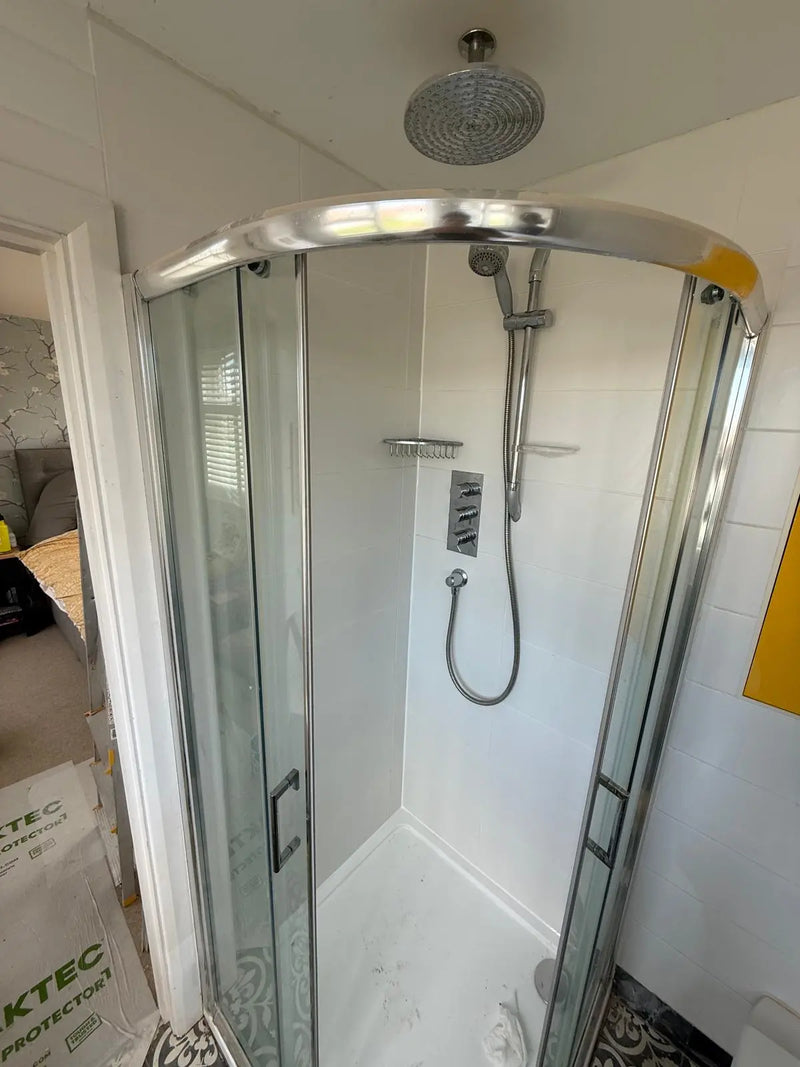 Restored quadrant shower cubicle with new white tiling, chrome thermostatic valves, and a rainfall showerhead after emergency leak repair by ODS.