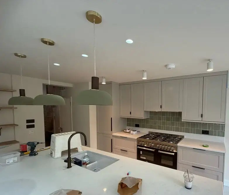 Sage green shaker kitchen with quartz island, range cooker, green metro tiles and pendant lights in a London home by ODS Plumbing & Construction
