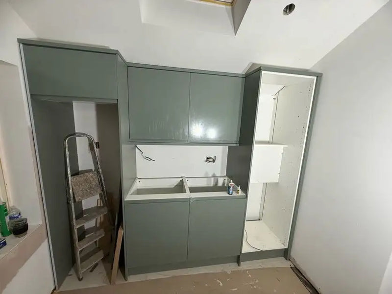 Sage green handleless utility room cabinets with wall units and open shelving being fitted in a London property by ODS Plumbing & Construction