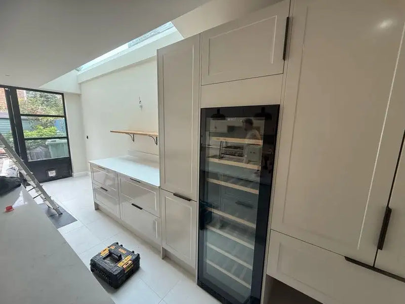 Cream shaker kitchen with integrated wine cooler, floor-to-ceiling tower units and rooflight in a London extension by ODS Plumbing & Construction