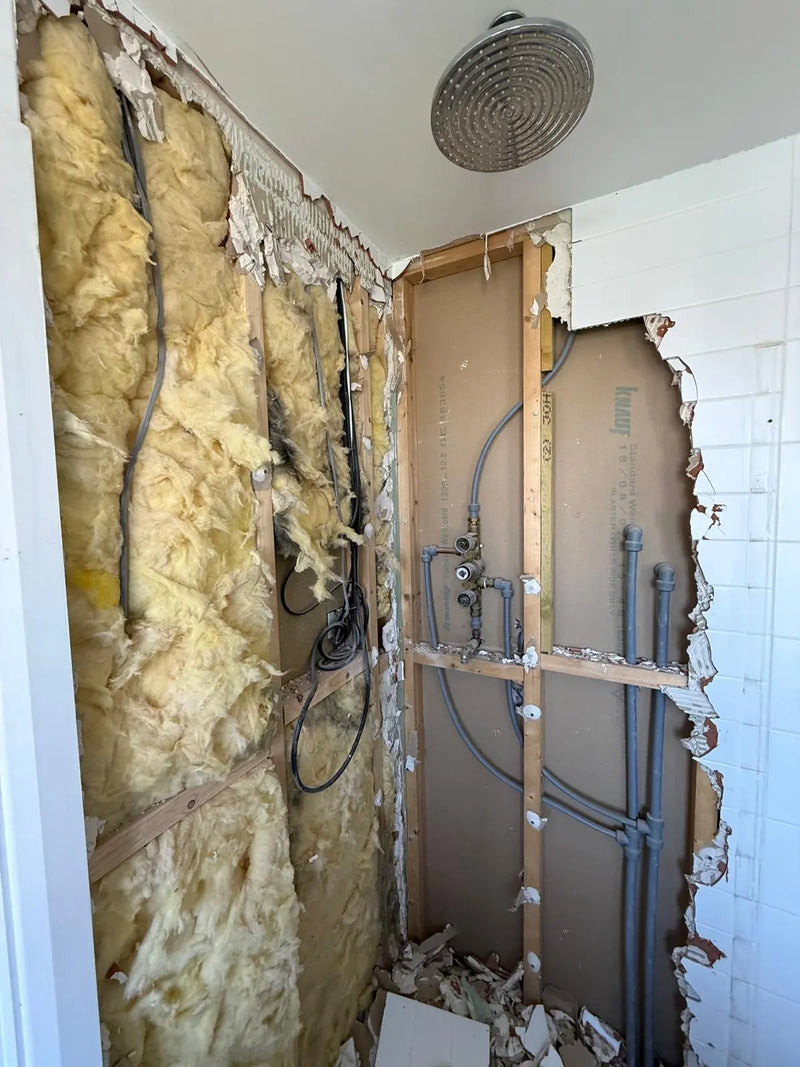 Exposed wall studs, insulation, and internal plumbing during a trace and access investigation for a shower leak by ODS Plumbing & Construction.